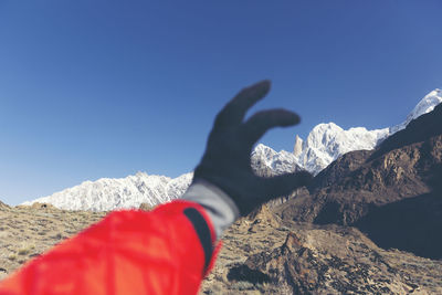 Cropped hand gesturing against snowcapped mountains