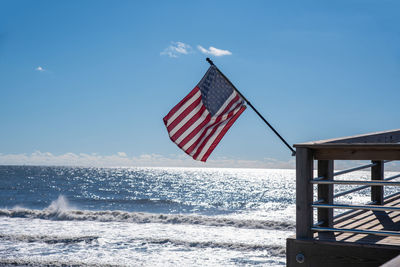 Scenic view of flag and sea against sky