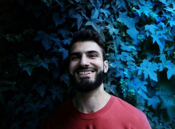 Portrait of smiling young man standing against plants