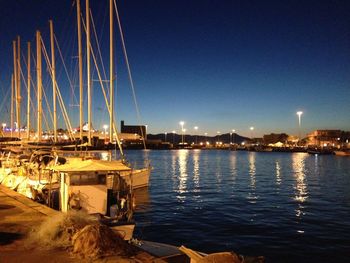 Boats moored at harbor in city at night