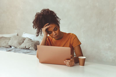 Young woman using laptop while sitting on sofa at home