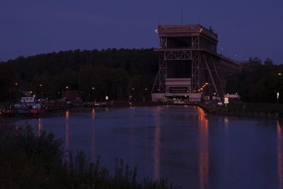 Illuminated building by lake at night