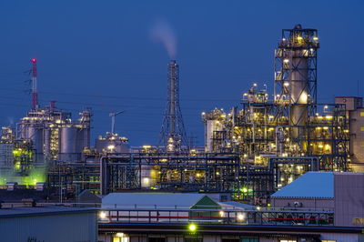 Illuminated factory against sky at night