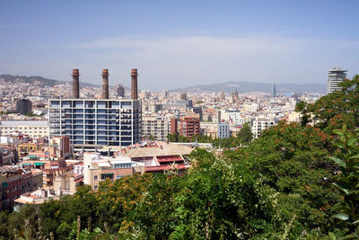 Trees and buildings in city against sky