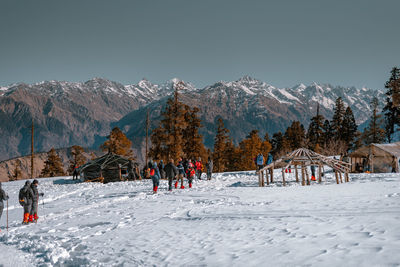 People on snowcapped mountain against sky