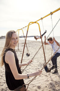 Portrait of woman playing swing at beach
