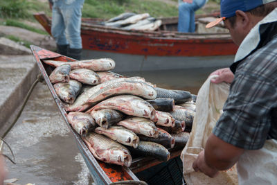 Mature man sitting with fish in boat on lake