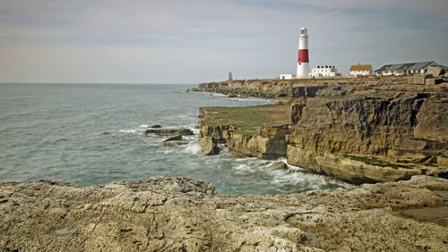 Lighthouse by sea against sky