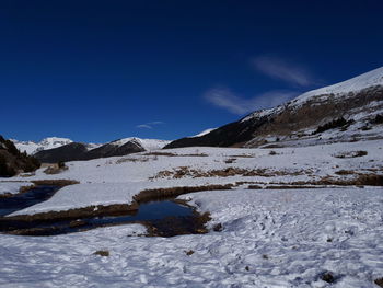 Scenic view of snowcapped mountains against blue sky