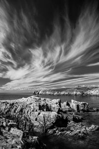 View of rocky coastline against cloudy sky