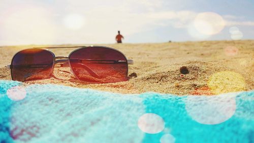 Close-up of sunglasses against sky on beach