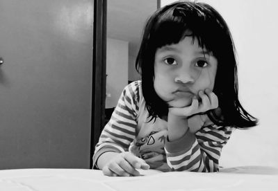 Portrait of girl sitting on table at home