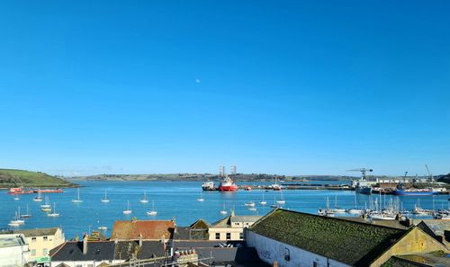 Sailboats in sea against buildings in city