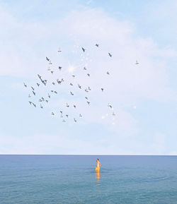 Rear view of woman standing at beach against sky