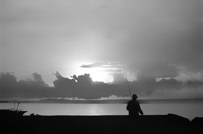 Silhouette man in sea against sky