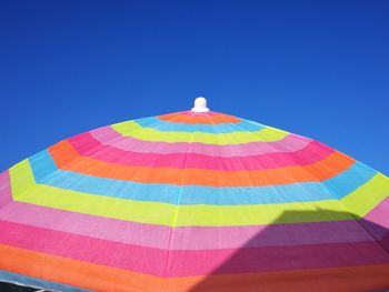 Low angle view of multi colored umbrella against clear blue sky