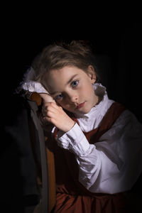 Portrait of girl looking away against black background