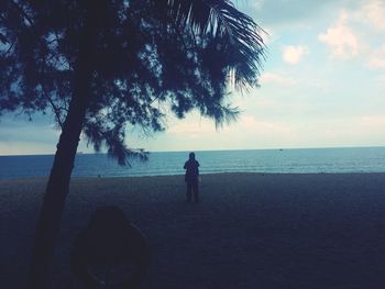 Rear view of man standing by sea against sky