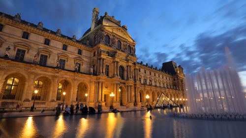 Illuminated musee du louvre against sky during dusk