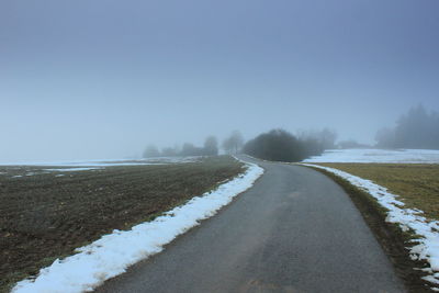 Empty road along snow covered landscape