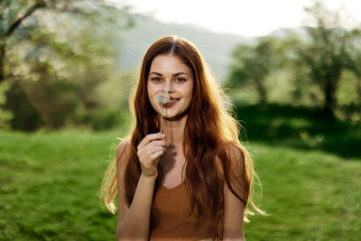 Portrait of young woman standing against trees