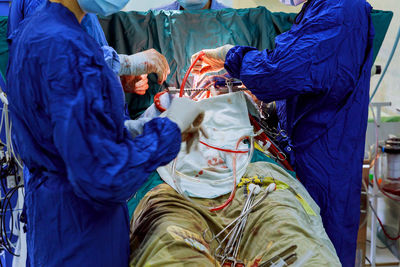 Midsection of doctors performing operation on patient in operating room