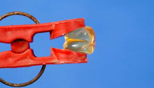 Close-up of red clothespin against blue background