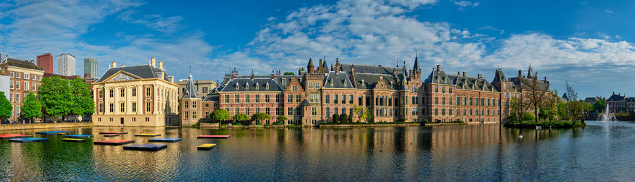 Buildings by river against sky