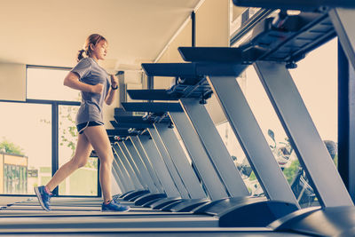 Full length of woman running on treadmill at gym