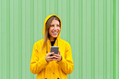 Young woman using mobile phone against green background