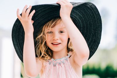 Candid portrait of a young girl laughing playing with a large sun hat