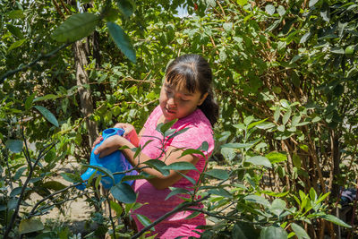 Side view of young woman standing amidst plants