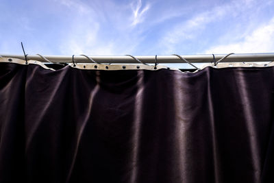 Low angle view of curtain on pole against sky