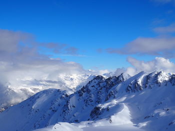 Scenic view of snow covered mountains against blue sky