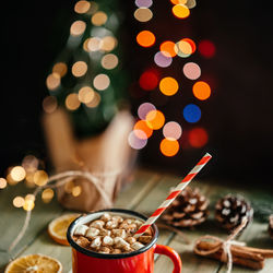 Red enamel mug of hot chocolate with marshmallow on christmas background