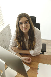 Young woman in glasses sitting on her hone workplace 