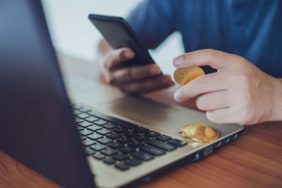 Midsection of man using mobile phone on table