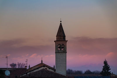 Clock tower amidst buildings against sky during sunset