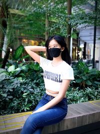 Portrait of young woman standing against plants