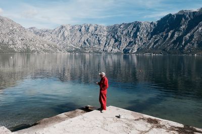 Rear view of woman on lake against mountain range