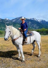 Portrait smiling mid adult woman sitting on white horse