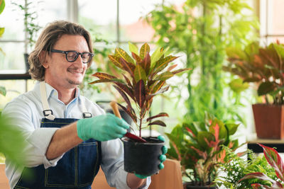 Portrait of smiling man holding potted plant
