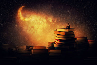 Stack of books on table against sky at night