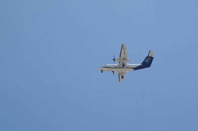 Low angle view of airplane flying against clear blue sky