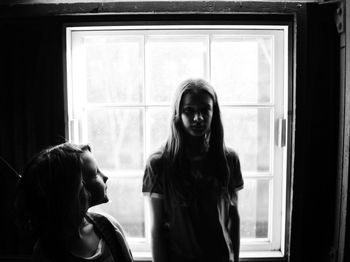 Girl standing against window