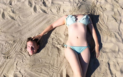 High angle view of young woman lying on sand