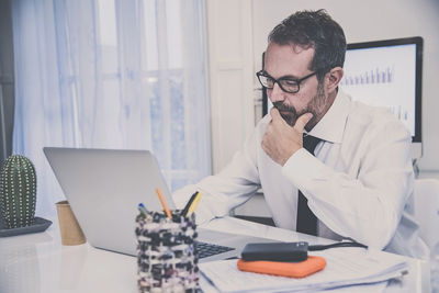 Business man works with laptop sitting at the desk. male at computer work online with remote office