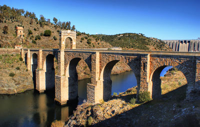 Arch bridge over river against clear blue sky