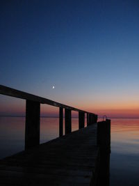 Bridge over sea against clear sky at sunset