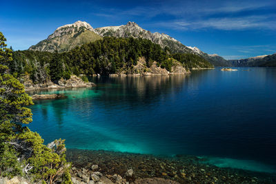 Scenic view of lake and mountains against blue sky